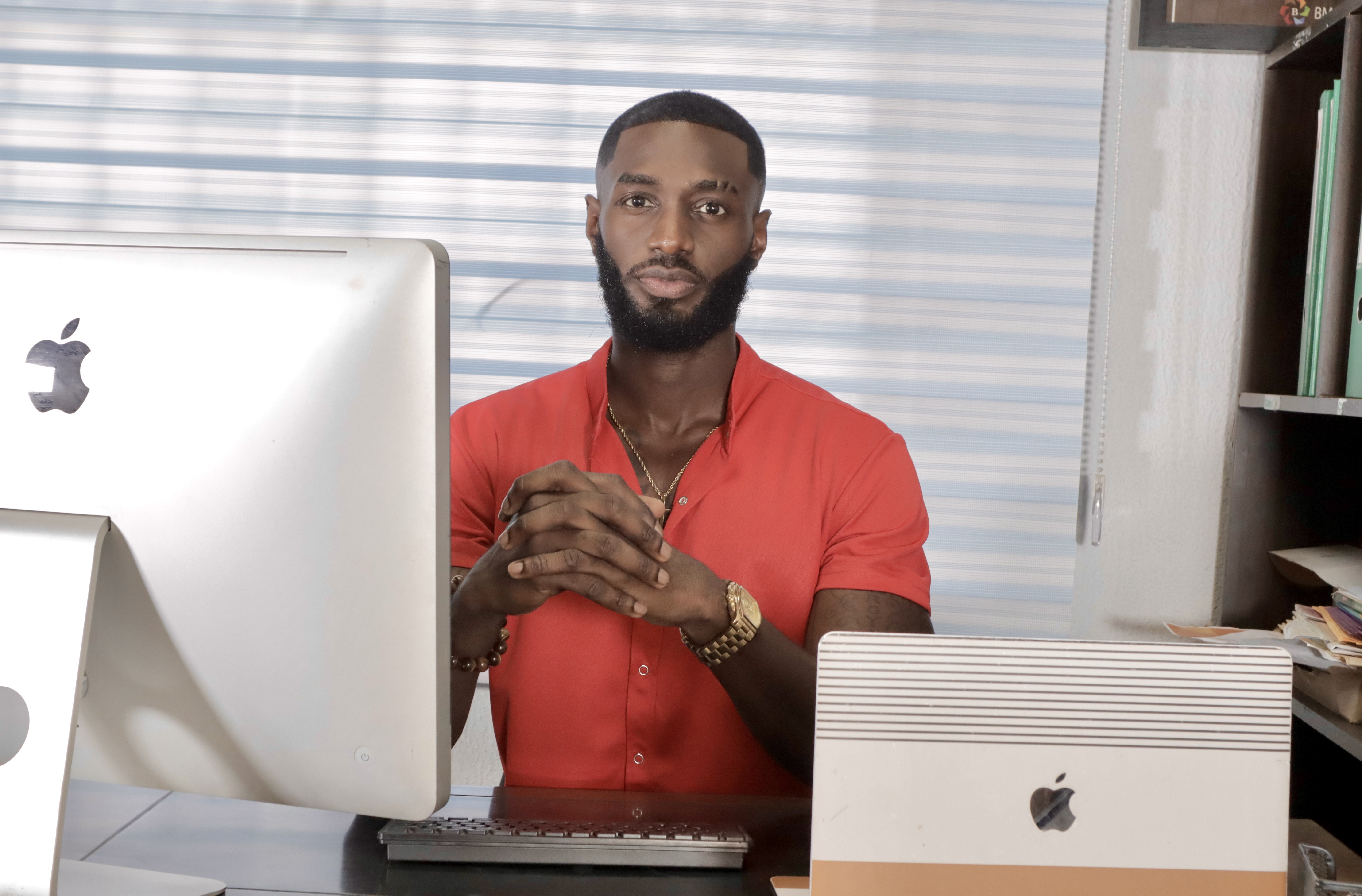 Benedict Osei-Bonsu, known as Benny Osbon, smiling in a red shirt in his office