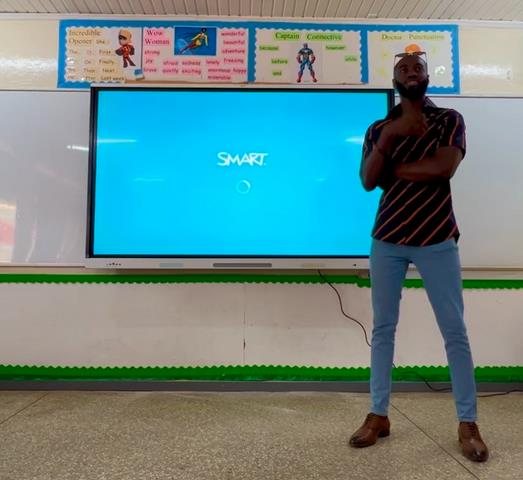 A team member standing beside a SMART interactive board in a classroom
