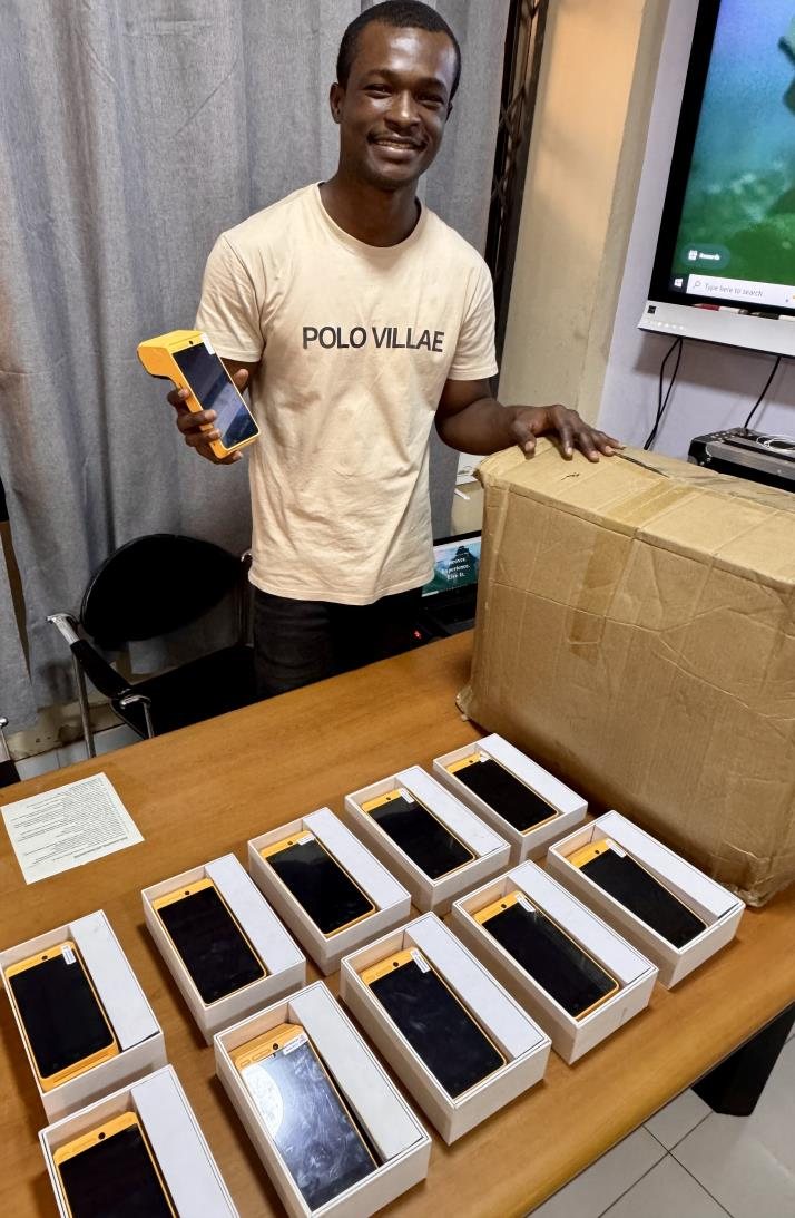 A team member holding a POS machine in front of a table of boxed devices