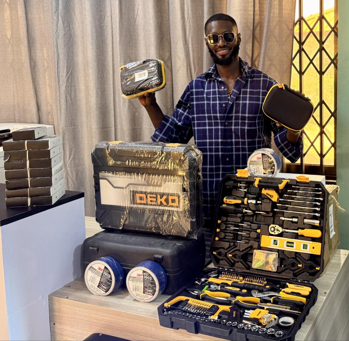 A team member holding a toolbox beside tool sets and tape rolls supplied to Saron Mobility